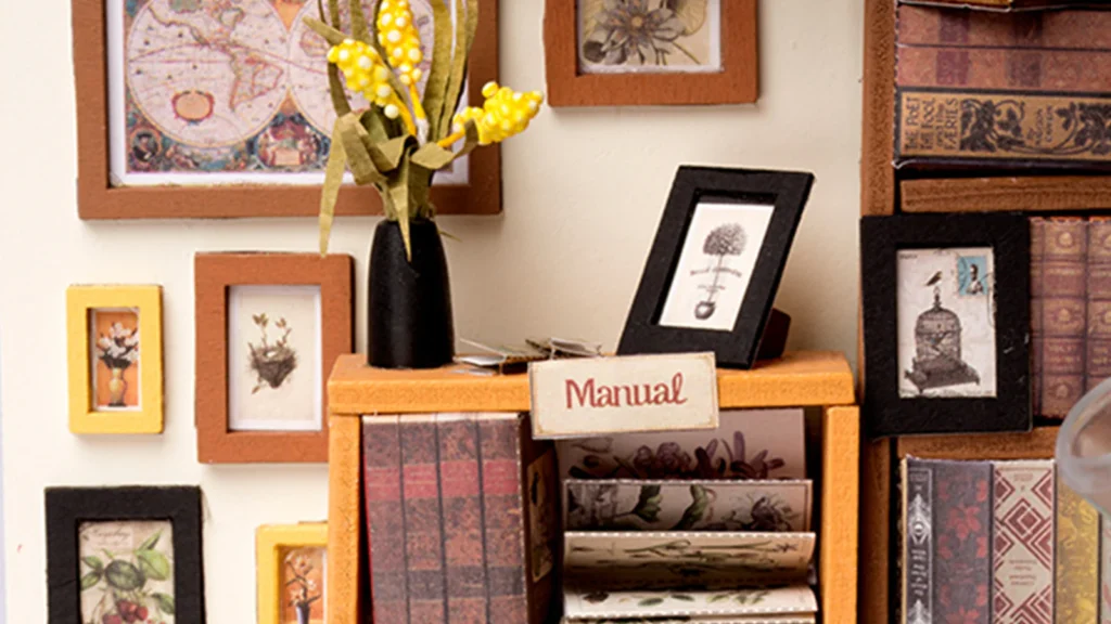 Close-up of a wall covered with framed decorative pictures in the Rolife Sam's Study Library DIY Miniature House Kit.