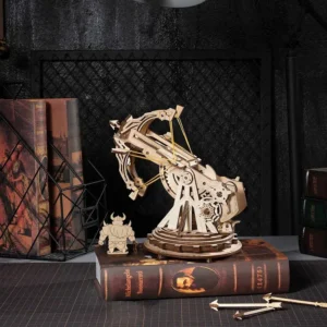 Siege Heavy Ballista 3D Wooden Puzzle on antique book of Michelangelo Buonarroti on desk with dark brown grid table mat. Antique books on left, black metal grid against black wall.