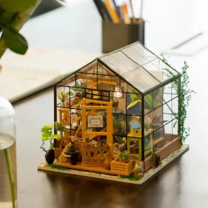 Cathy’s Flower House on wooden desk with subtle lighting, planner, pencil holder in background, and glass vase with green plant in foreground.