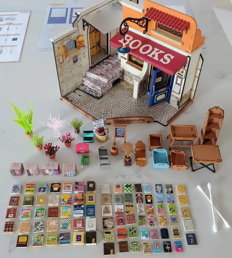 Partially assembled Rolife Corner Bookstore DIY Miniature House Kit with parts neatly laid out on a table.