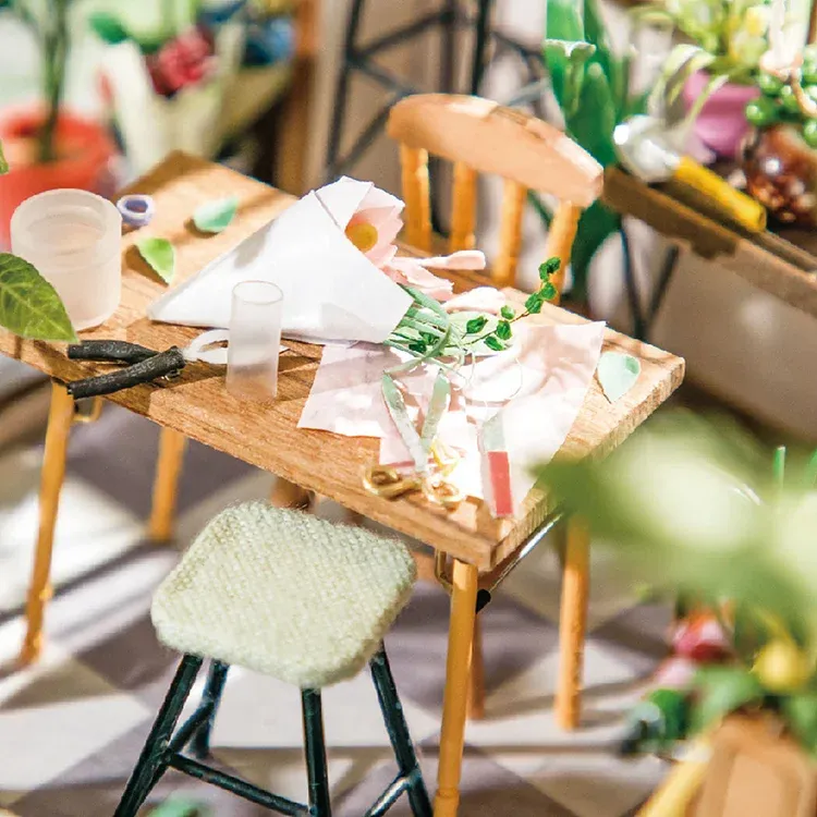 Close-up of Rolife Emily's Flower Shop Miniature House showing the charming assortment of miniature potted plants, shelves, crates, furniture, tools, and elements meticulously crafted to capture the essence of a real flower shop.